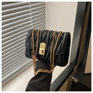 Detail of black pleated shoulder bag with gold chain strap and vintage square lock buckle