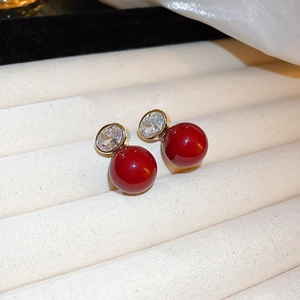 Macro detail of red pearl earrings with square crystal studs in a jewelry display box