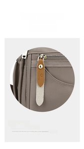 Detail of waterproof grey nylon bag with branded brown leather zipper pull and silver zipper