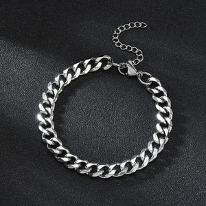Detail of silver Cuban link bracelet with lobster clasp and adjustable chain on dark background