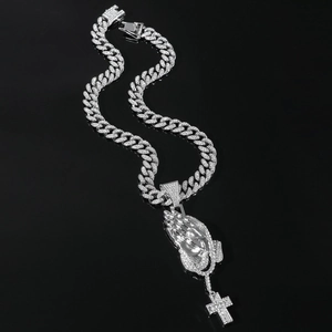 Macro shot of silver hip hop necklace with iced out praying hands and cross pendant