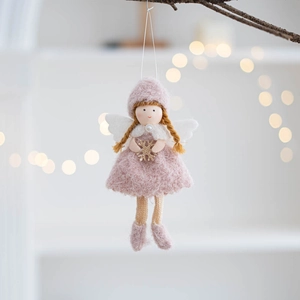 Detail of pink felt Christmas angel ornament with feather wings hanging on a tree branch