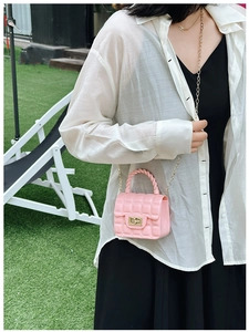 Pink quilted jelly bag with gold chain strap shown on a model in an outdoor setting