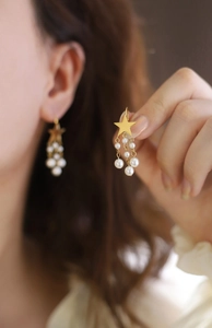 Detail of gold star earring with elegant cascading pearl tassels and hook finding