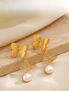 Macro detail of 18K gold butterfly earrings with zircon stones and white pearls