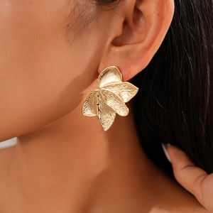 Detailed view of layered gold leaf earrings with textured metal finish on a model