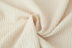 Macro detail of creamy off-white fabric with textured v-neck top pleats and soft grain