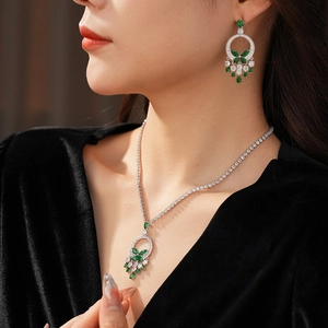 Gros plan d'un ensemble collier et boucles d'oreilles en argent avec émeraudes vertes