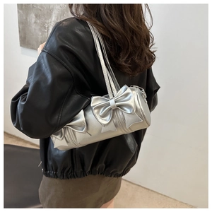 Silver bolster bag with large decorative bows and metallic finish on shoulder