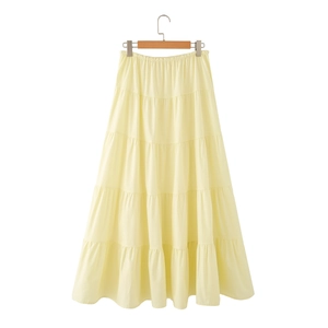 Detail view of pale yellow tiered maxi skirt with elastic waistband on a wooden hanger