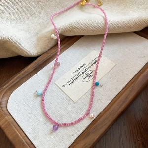 Detailed shot of pink beaded necklace with colorful accents on a rustic wooden tray