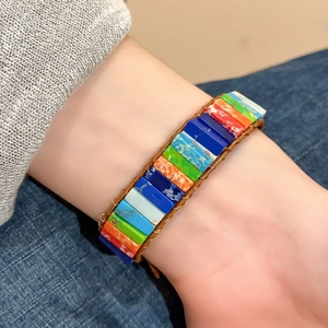 Détail d'un bracelet de perles carrées colorées sur cordon en cuir tressé porté