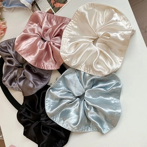 Detailed view of five silk-like satin oversized scrunchies in assorted pastel colors