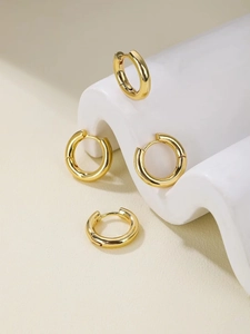 Detail of high-polished gold hoop earrings on a creative display stand with 2 pairs