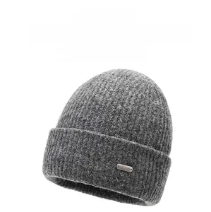 Close-up of dark grey knit beanie featuring a metal tag and thick ribbed texture