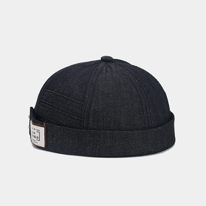 Detail of vintage denim docker hat featuring a textile logo patch and reinforced stitching