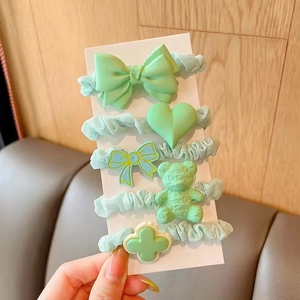Detail of 5-piece mint green hair scrunchies set featuring cute resin bear and bow charms