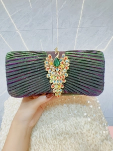 Detail of evening clutch featuring green pleated fabric and a crystal peacock ornament