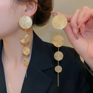Elegant gold-tone multi-circle tassel drop earrings featuring spiral texture on a female model