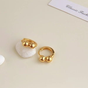 Detailed macro view of 18K gold plated huggie earrings with polished metal spheres