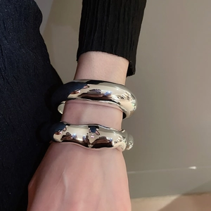 Close-up of silver irregular open cuff bracelets with smooth and molten lava textures