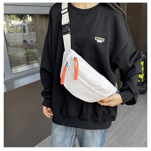 Detailed view of white canvas crossbody bag with orange zipper pulls and black buckle strap
