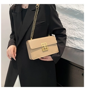 Detail of beige leather crossbody bag with golden chain strap and stylish square metal buckle