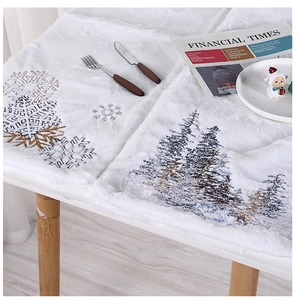 Close-up of white plush Christmas table runner with embroidered snowflakes and pine trees