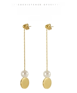 Detail of long pearl tassel earrings featuring gold metal chains and round pendants