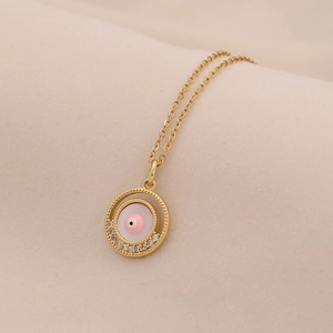 Dettaglio del ciondolo malocchio dorato con smalto rosa e cristalli scintillanti
