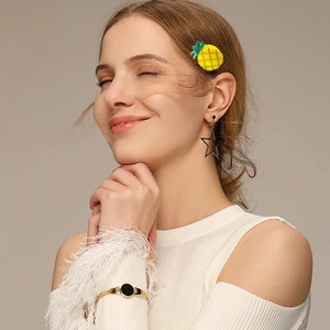 Detail of yellow pineapple hair clip and star earring worn by model in white knit