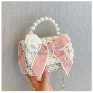 Close-up of girls' tweed handbag with pink bow, camellia flower and pearl handle