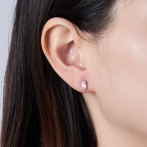 Close-up of minimalist gold-plated rectangle earring with step-cut zircon on model ear