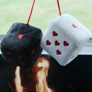 Close-up of black and white plush hanging dice with red embroidered heart patterns