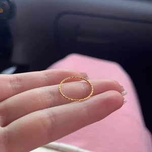 Minimalist gold titanium steel ring with textured finish shown on finger in daylight