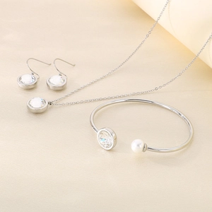 Detail of silver jewelry set with round clear stones and pearl on silk background