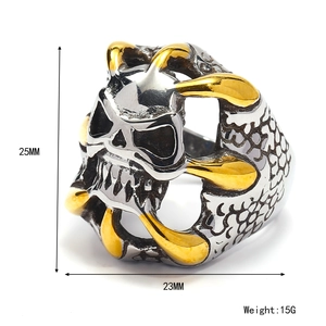 Gothic skull ring in silver stainless steel with golden claw accents on white background
