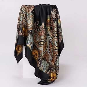 Detailed view of paisley silk scarf draped over a white cube with satin sheen finish
