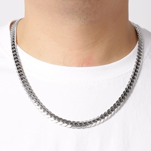 Close-up of polished silver stainless steel Cuban link necklace worn by a male model