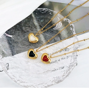 Detailed view of heart-shaped pendants in white, black and red on gold satellite chains