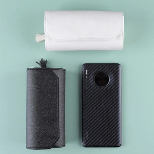 Portable leather jewelry roll organizer in black and white shown next to a phone for scale
