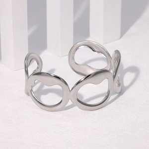 Macro detail of silver irregular hollow open cuff bracelet on white geometric pedestal
