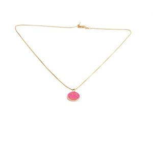 Detail of gold chain necklace with a pink enamel happy face charm and clasp on white