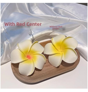 Detail of plumeria hair clips in white and yellow foam on a wooden tray