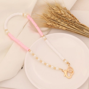 Detailed shot of pink and white clay beads with pearls and golden heart clasp