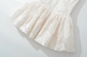 Detailed macro view of the white floral embroidery and ruffled hemline textures
