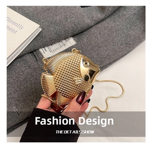 Detail of golden fish-shaped metal evening clutch with fine scale texture and chain