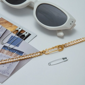 Detail of gold zircon bracelet with safety pin clasp design and square gemstones