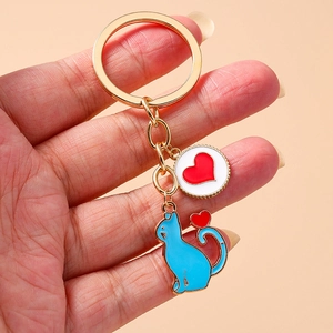 Cute metal cat and red heart pendant keychain with gold ring on a beige background