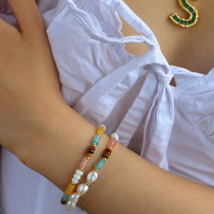 Detail of layered bohemian bracelets with natural pearls and colorful amazonite beads